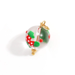 Detail of a transparent sphere charm featuring red strawberry patterns and gold fittings