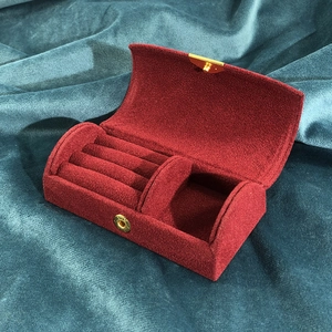 Close-up of red velvet jewelry box interior with ring slots and storage compartment