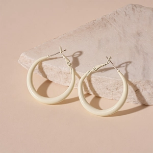Close-up of cream resin hoop earrings on a natural stone base with soft lighting