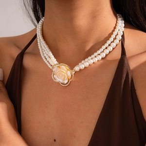 Detailed view of layered pearl necklace featuring a diamond-encrusted flower pendant