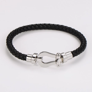 Dettaglio di un bracciale in pelle intrecciata nera con chiusura a ferro di cavallo in argento