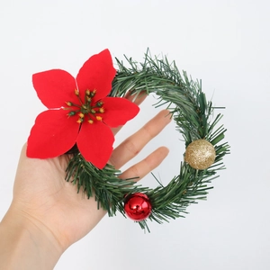 Mini Christmas wreath with red poinsettia and glittery gold ornaments held in hand