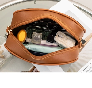 Internal compartment view of brown leather crossbody bag with daily essentials and gold zipper