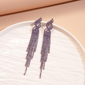 Macro shot of purple tassel drop earrings with sparkling rhinestones on ceramic tray