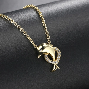 Golden dolphin necklace with sparkling zircon ring pendant on a black textured background