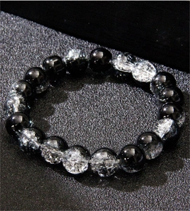 Detailed close-up of alternating black and white cracked glass beads on a stretch bracelet