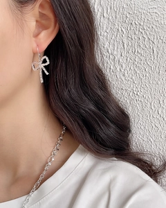 Close-up of 925 sterling silver bow earrings with zircon stones on a model's ear