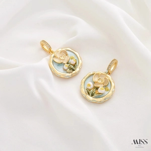 Macro view of floral enamel pendant with creamy flowers and pearls on white silk
