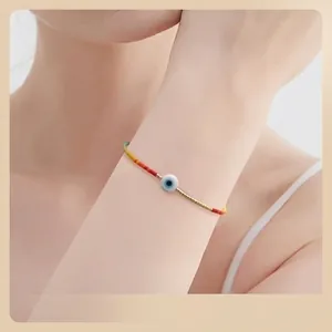 Bracelet œil porte-bonheur minimaliste avec perles colorées et segments dorés au poignet
