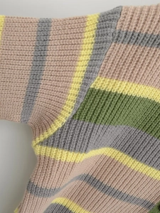 Close-up detail of coarse knit texture and multicolor striped pattern on the cardigan