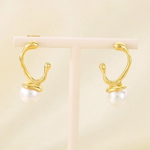 Detail of golden irregular streamline earrings with round white pearls on a display stand