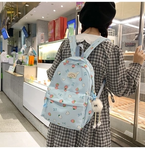 Rear view of a light blue strawberry pattern backpack worn by a student in a shop