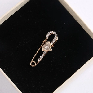 Macro view of a gold safety pin brooch with sparkling crystals on velvet padding