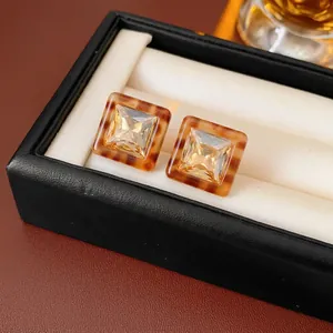 Vintage tortoiseshell resin square stud earrings with champagne crystal on black leather