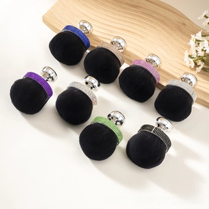 Detail of rhinestone-encrusted makeup brushes in various colors on wooden tray