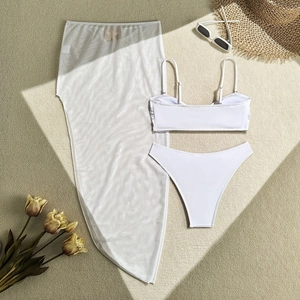 Piatto di un bikini bianco a tre pezzi con gonna in rete velata e accessori da spiaggia