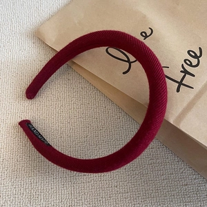 Close-up of wine red corduroy headband with handmade label on beige fabric background