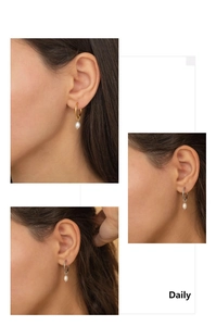 Detail of elegant 18K gold plated hoop earrings with drop-shaped white pearls for women