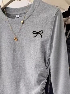 Minimalist grey long-sleeve knit top with black butterfly embroidery on the chest