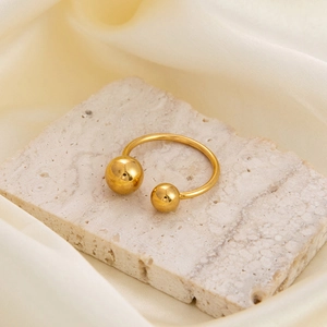 Minimalist 18K gold plated stainless steel ball ring on stone and silk background