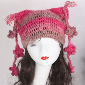 Detail of handmade striped crochet cat ear hat with pink tassels and knitted flower accents