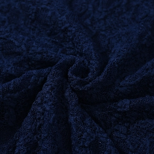 Macro close-up of dark blue lace fabric with detailed floral patterns and elegant texture