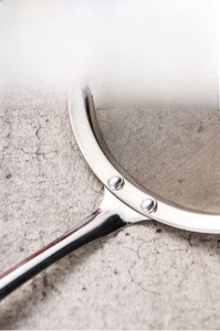 Close-up of stainless steel skimmer showing reinforced rivet joints and fine mesh detail
