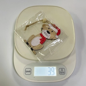 Detailed view of dog Christmas wood ornament on digital scale weighing 3.9g with twine