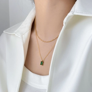 Double-layered gold titanium necklace featuring a rectangular emerald green gemstone pendant