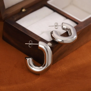 Polished silver stainless steel thick U-shaped hoop earrings on a vintage jewelry box