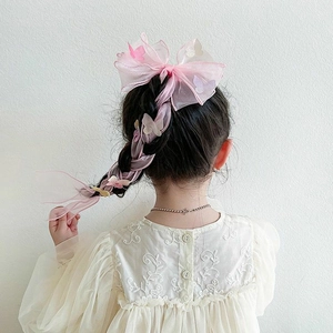 Detail of pink tulle bow hair clip with butterfly ornaments braided into a girl's hair
