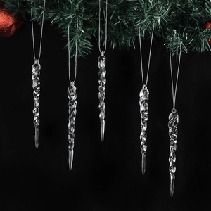 Five transparent icicle Christmas ornaments hanging on a green festive pine branch