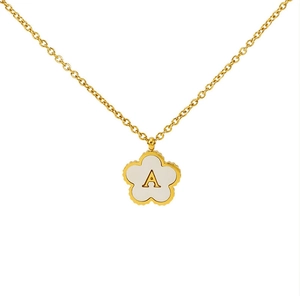 Detailed macro of golden clover necklace featuring white enamel shell with letter A