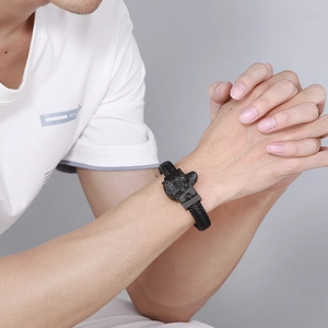 Detail of men's braided leather bracelet featuring a vintage silver wolf head buckle