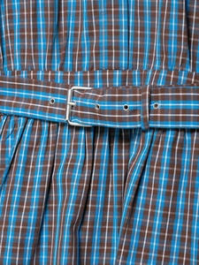 Détail de la taille d'une robe à carreaux avec ceinture assortie et boucle argentée