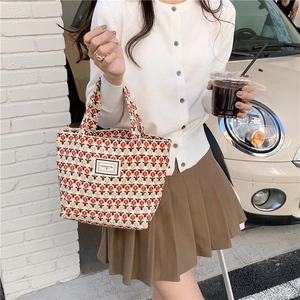 Retro corduroy handbag with red tulip pattern and woven label shown in a street setting