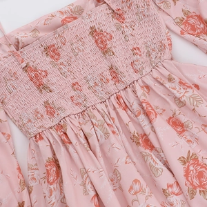 Gros plan d'une robe rose à fleurs avec smocks élastiques et détails de volants