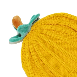 Macro shot of yellow thick knit texture and green velvet plant stem detail on the pumpkin hat