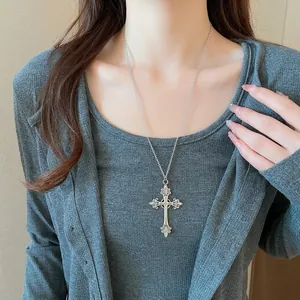 Gothic cross necklace with intricate lily motifs and vintage silver finish on model