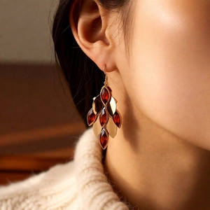 Macro detail of 18K gold-plated teardrop earrings with red crystals worn on model