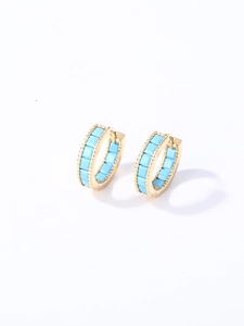 Detalle de pendientes de aro chapados en oro con esmalte azul cielo sobre fondo blanco
