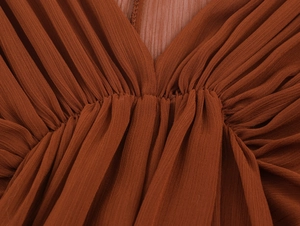 Nahaufnahme von plissiertem Chiffon in Karamell mit feiner vertikaler Textur und Handwerk