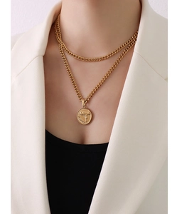 Detail of double-layer Cuban chain necklace with a gun relief coin pendant in 18k gold
