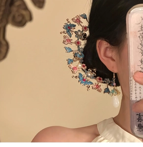 Détail d'une épingle à cheveux fleur papillon élégante avec perles portée par un modèle