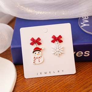 Detail of Christmas snowman and snowflake earrings with festive red bows and enamel finish