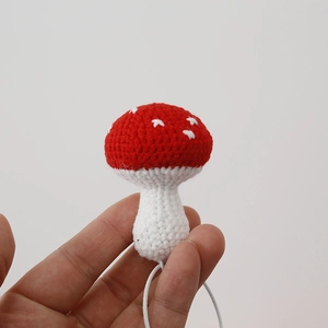 Handmade crochet red mushroom keychain pendant with white polka dots on soft wool yarn