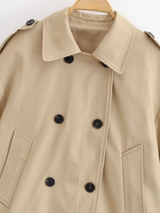 Close-up of khaki trench coat featuring double-breasted buttons and epaulette shoulder details