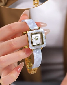 Nahaufnahme der goldenen quadratischen Damenuhr mit Marmor-Resin-Armband im Retro-Stil