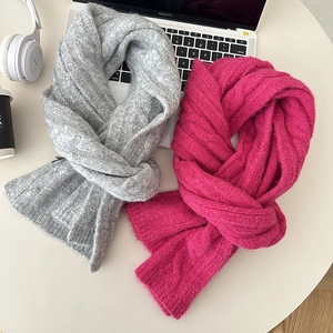 Detail of grey and pink cable knit wool scarves with crossed design in a cozy setup