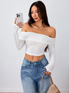 Detail van witte crop top met blote schouders en fijne opengewerkte textuur